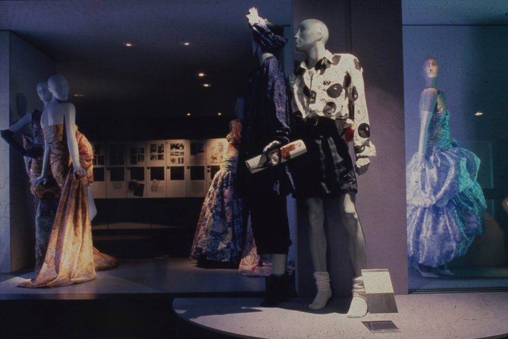 Mannequins dressed in feminine garments in a dimly-lit room