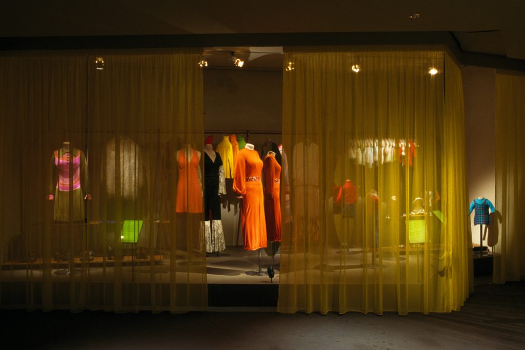 Exhibition display of mannequins behind gauze curtains