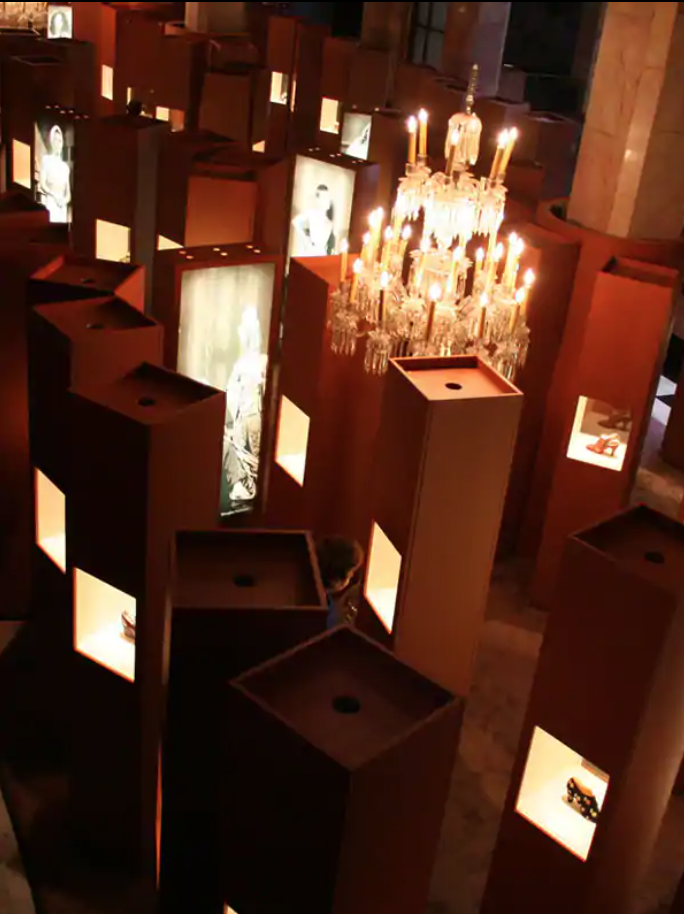 Exhibition display of plinths from above, interspersed with screens and some with shoes visible