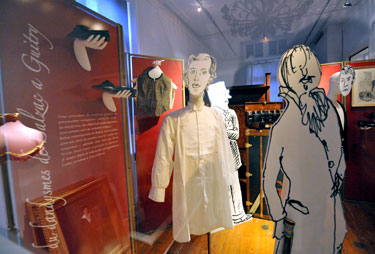 Exhibition display of dressed mannequins with drawn cut outs of heads and bodies
