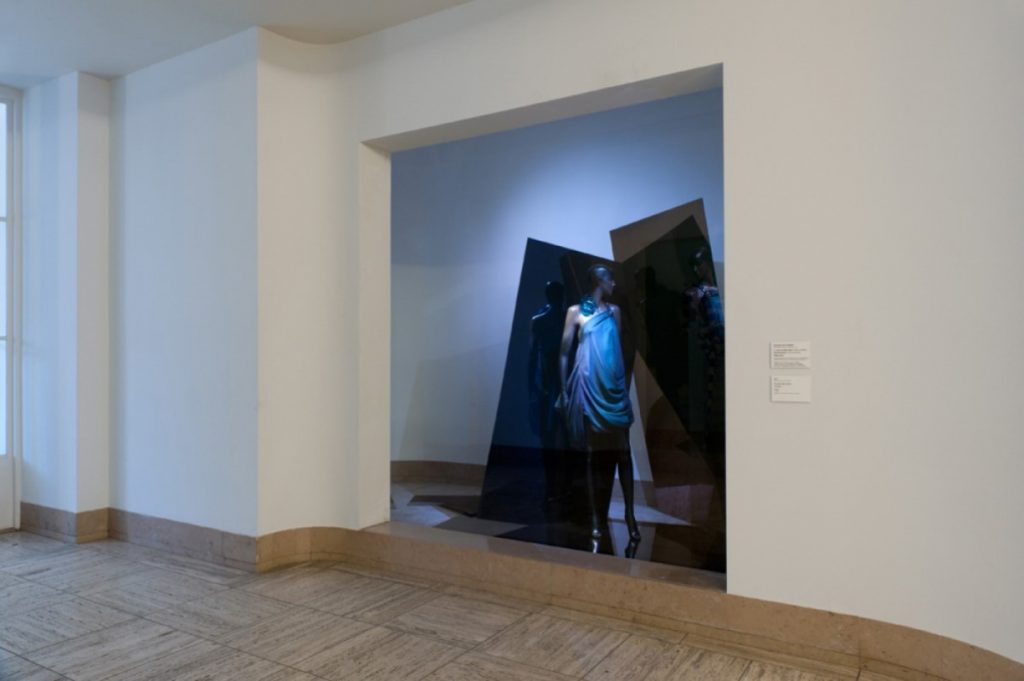 Exhibition display of dressed mannequin framed in an alcove