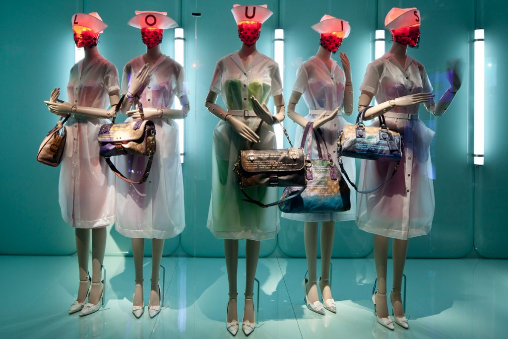 Exhibition display of five dressed mannequins holding bags