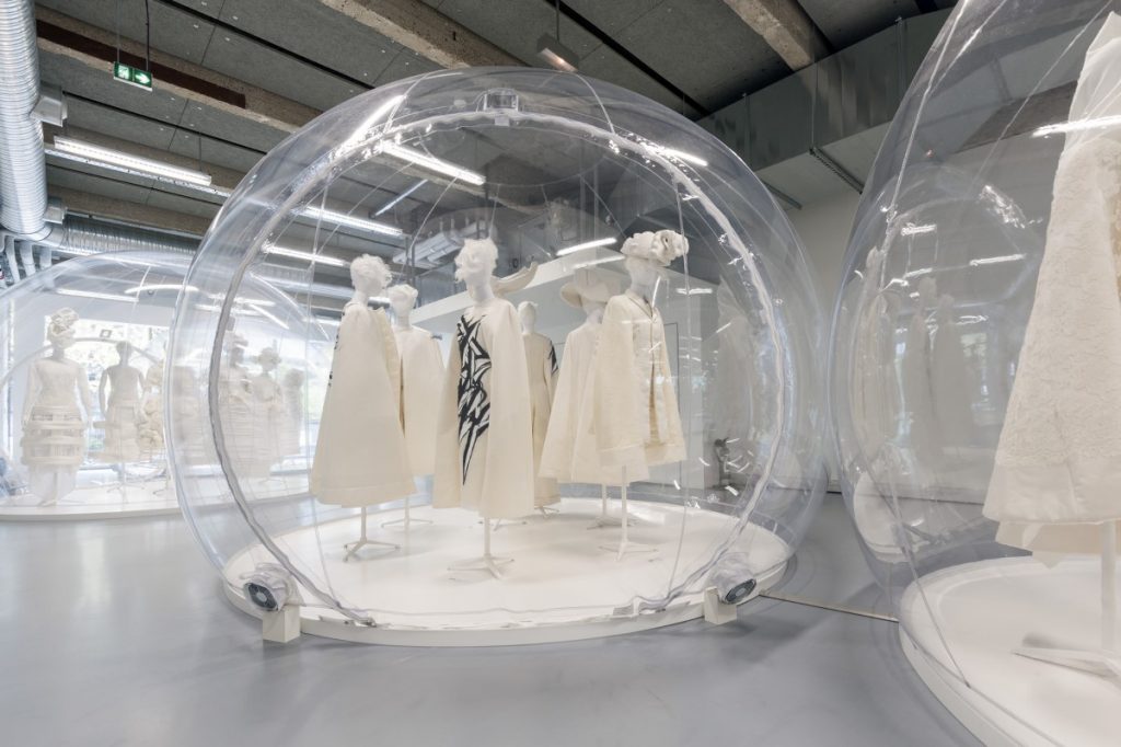 Exhibition display of mannequins dressed in white in perspex bubbles