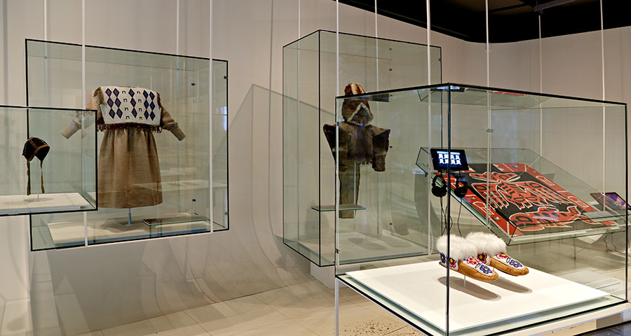 Exhibition display of dressed mannequins and garments in glass cases