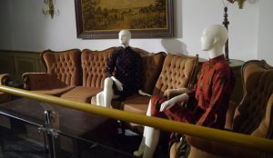 Exhibition display of dressed mannequins seated on sofa