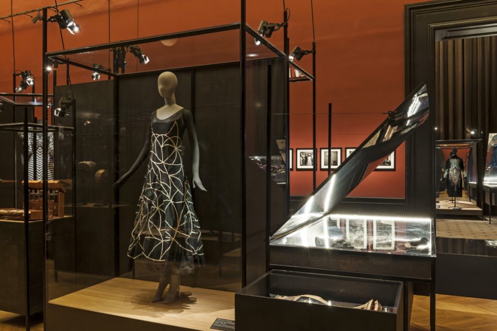 Exhibition display of dressed mannequins framed by metal surrounds