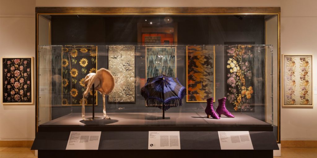 Exhibition display of hats and boots in glass case