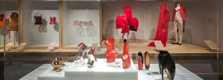 Five pairs of shoes, including traditional Japanese 'Geta' and Alexander McQueen 'Armadillo' boots from Plato's Atlantis, are displayed in front of a range of outfits.