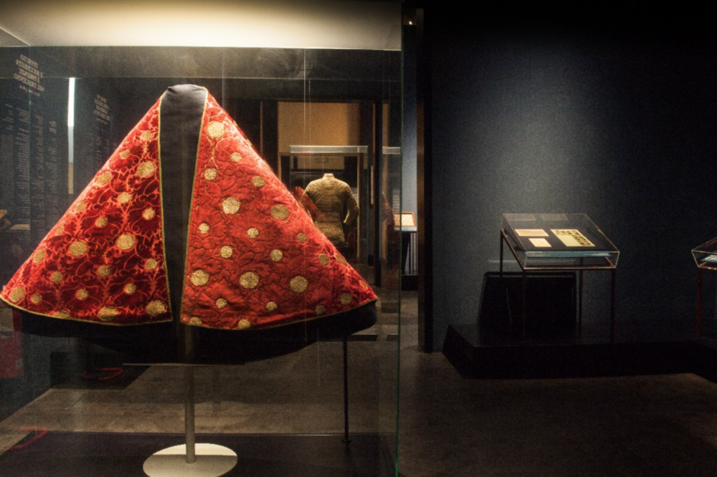 Exhibition display of red cape with gold design