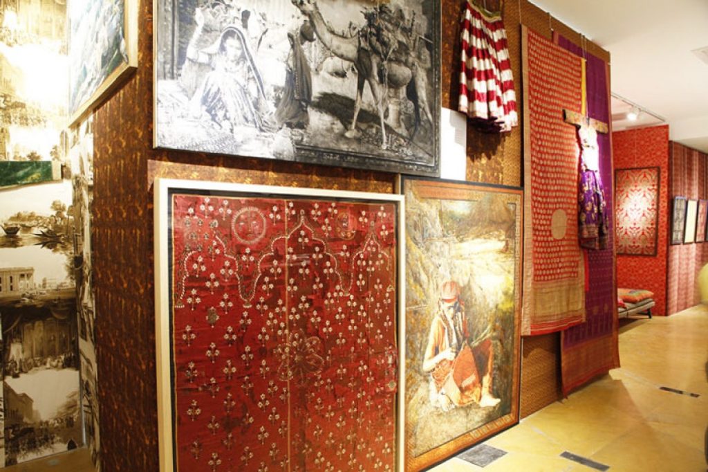 Exhibition display of garments alongside paintings
