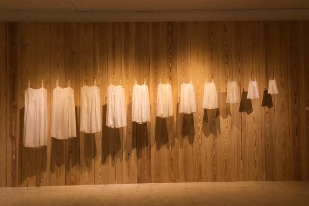 Exhibition display of white dresses hanging