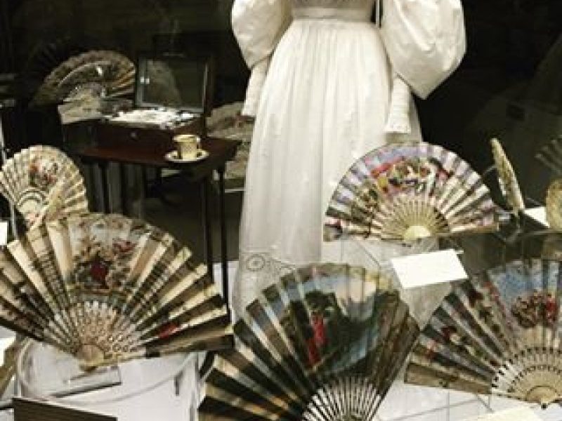 Exhibition display of fans in foreground of dressed mannequin