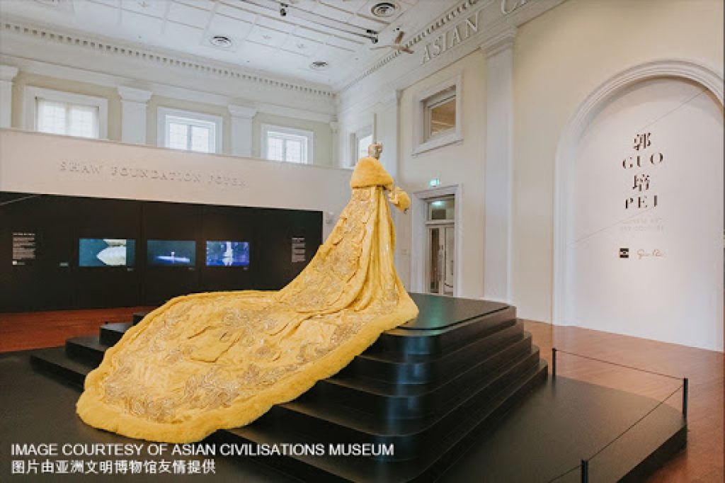 Exhibition display of mannequin in gold ensemble on a plinth