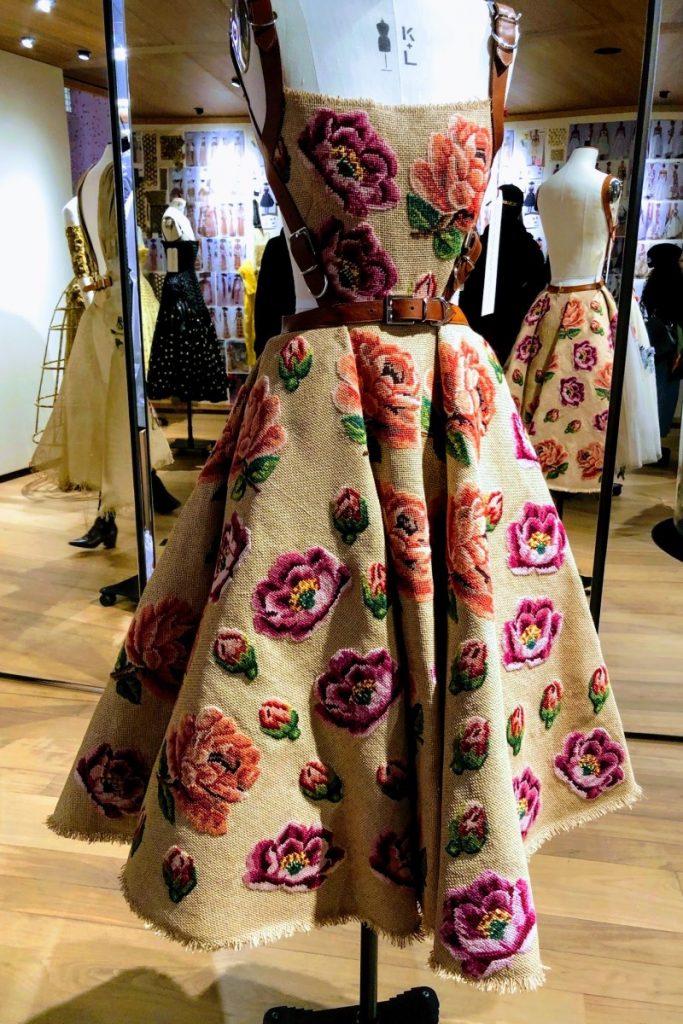 Exhibition display of dressed mannequin in rose tapestry dress