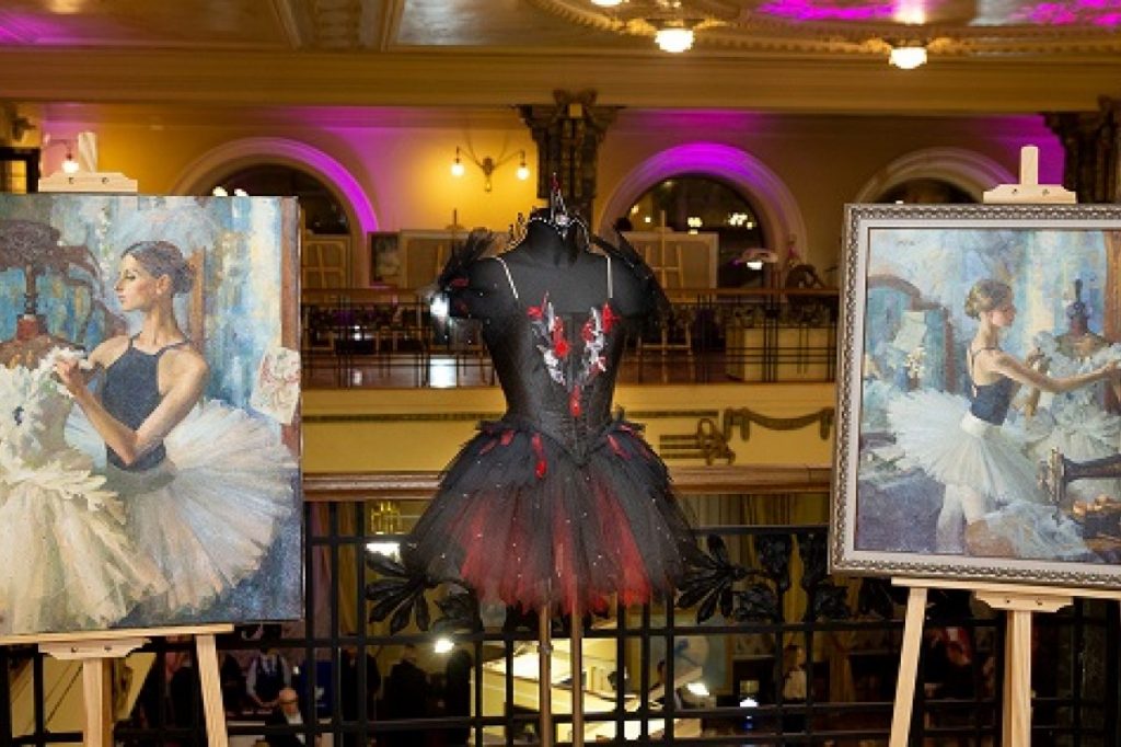 Exhibition display of dressed mannequin with paintings depicting ballet scenes on either side