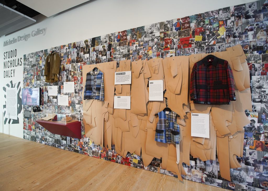 A wall of plaid clothing hung over a background of design patterns and photographs