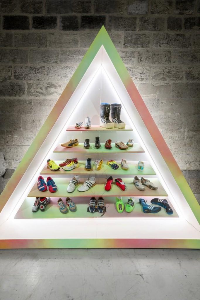 Exhibition display of trainers in a triangle-shaped plinth