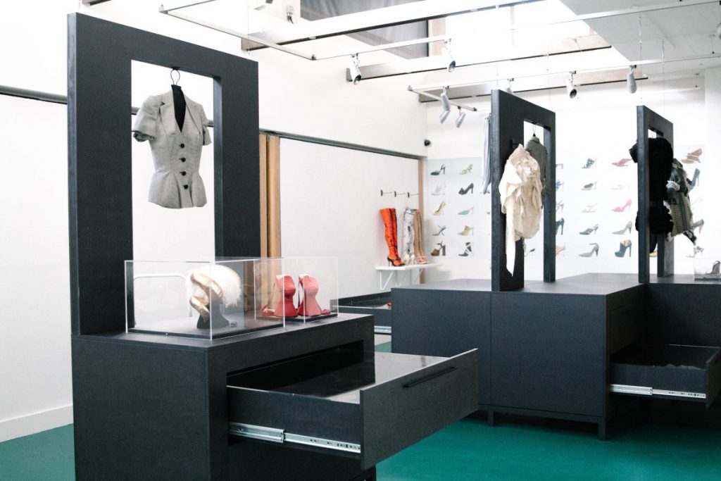 Exhibition display of clothes mounted on stands and open drawers