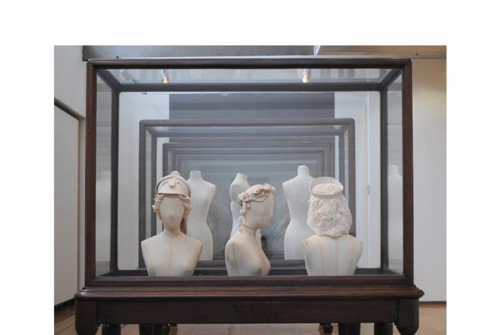 Exhibition case of calico covered mannequin busts with headdresses and of calico torsos
