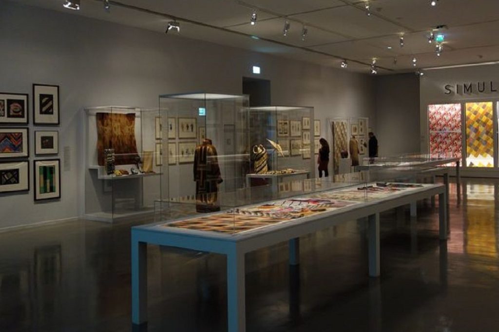 Exhibition display of glass cases containing textiles and garments