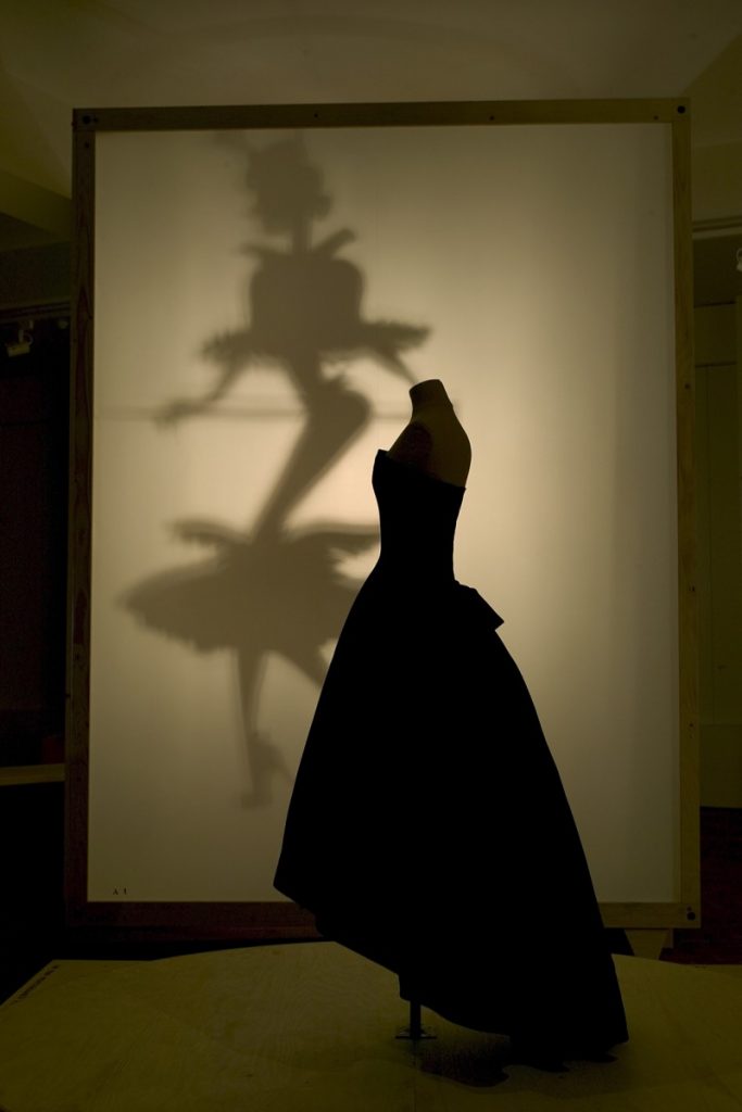 Exhibition display of dressed mannequin with projected fake silhouette