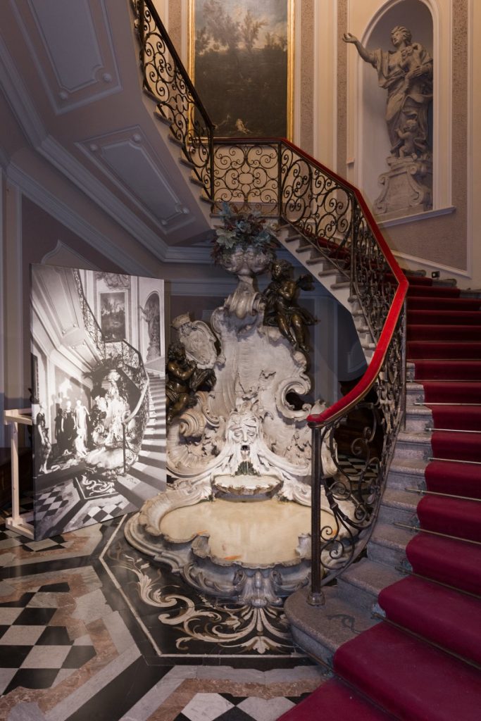 Exhibition display of tulip staircase with wrought iron handle with a picture of the same scene leaning against it