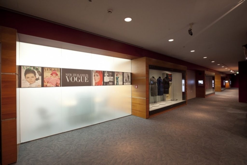 Exhibition display of wooden cabinets framing introductory panels of Vogue covers anddressed mannequins