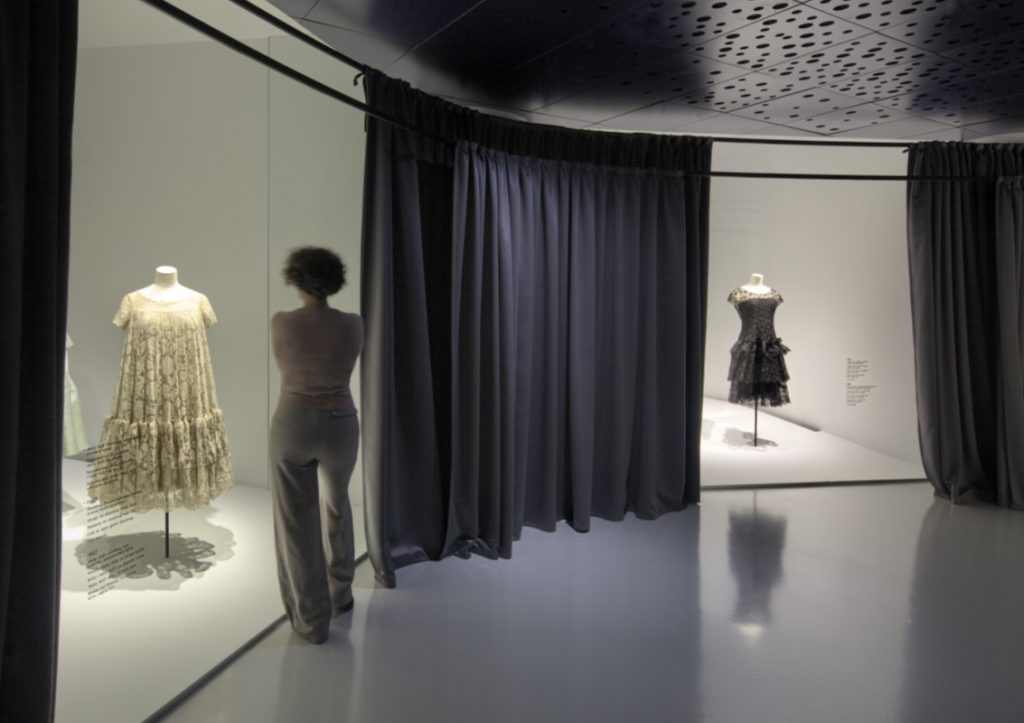 Exhibition display of dressed mannequins and person viewing