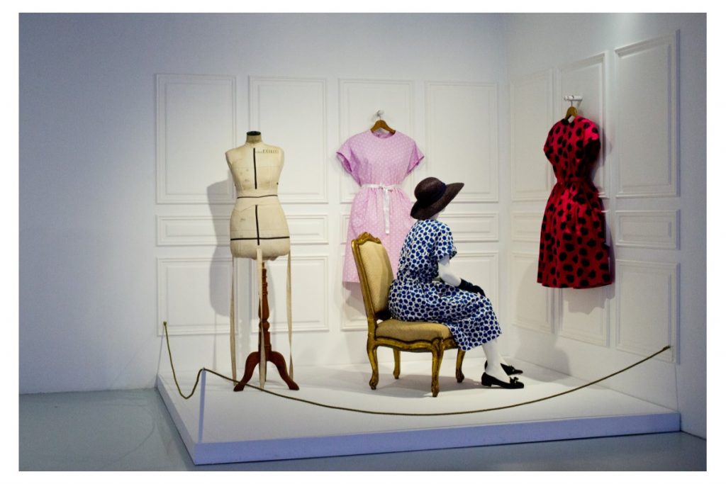 Exhibition display of dressed mannequins with one seated in chair