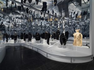 Exhibition with multiple mannequins reflected in a mirrored ceiling