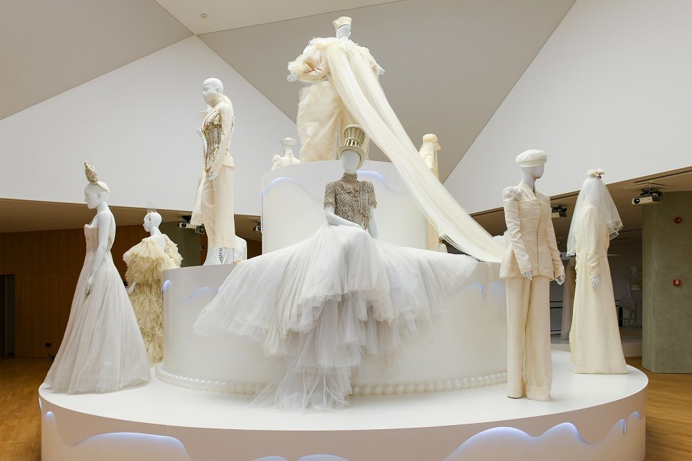 Exhibition display of a wedding cake style plinth with dressed mannequins in wedding attire