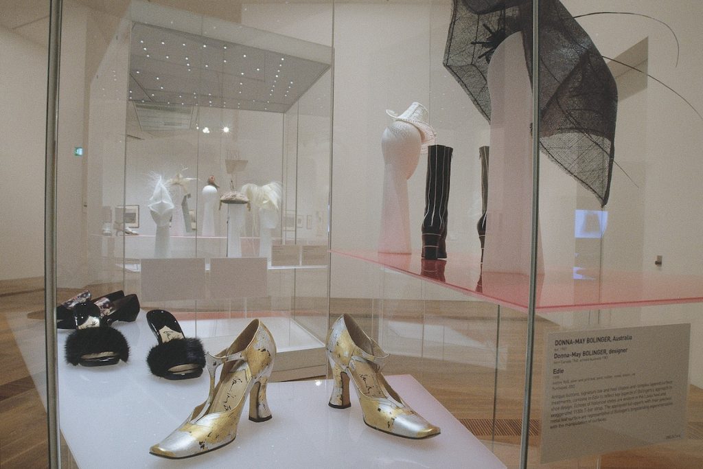 Exhibition display of footwear and headwear in glass case