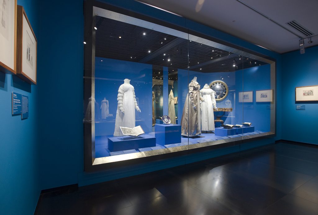 Exhibition of dress behind built in glass vitrine