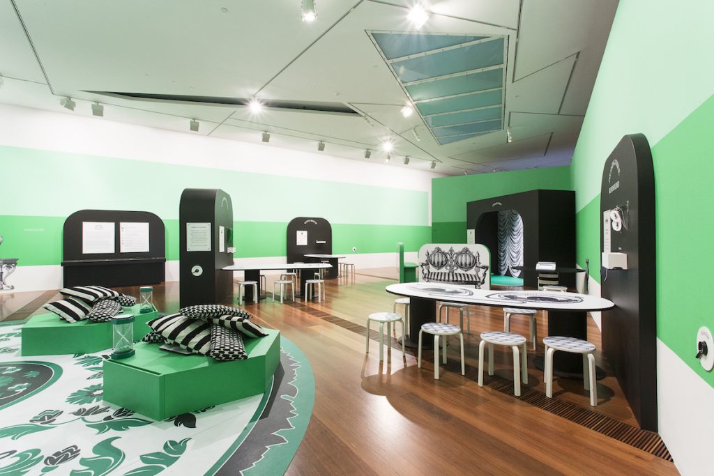 exhibition room painted green, white and black with tables and display boards
