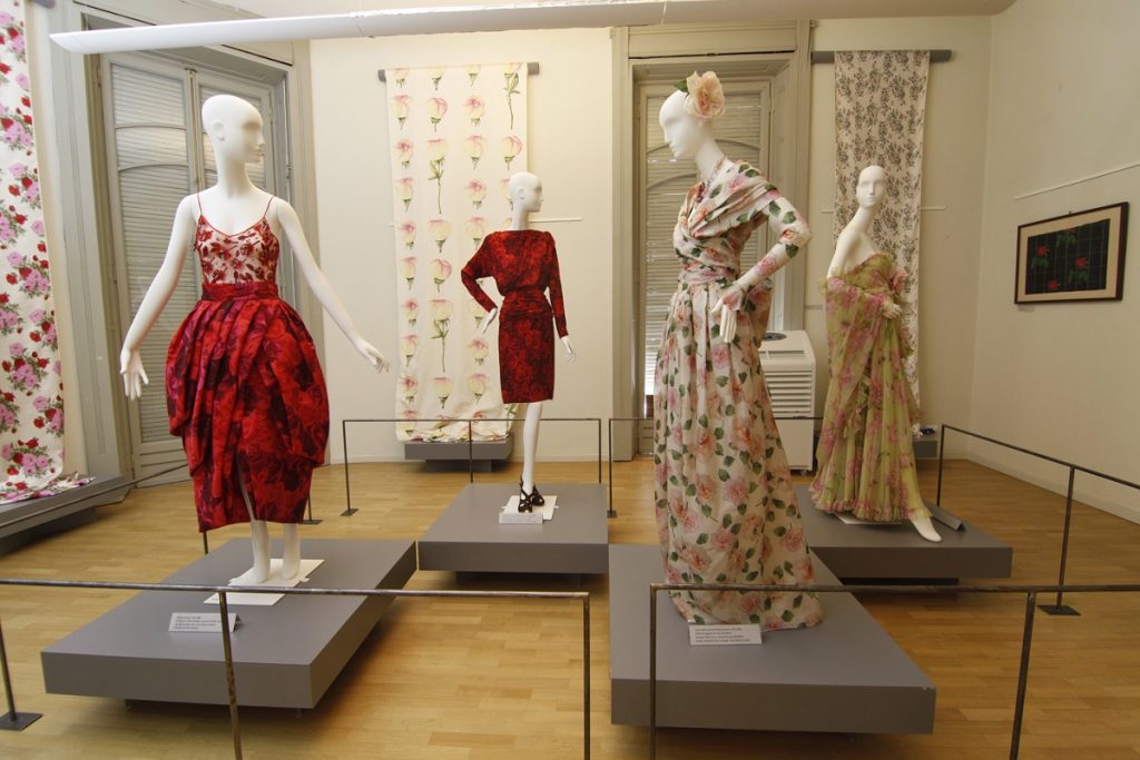 Exhibition display of dressed mannequins and textiles on wall