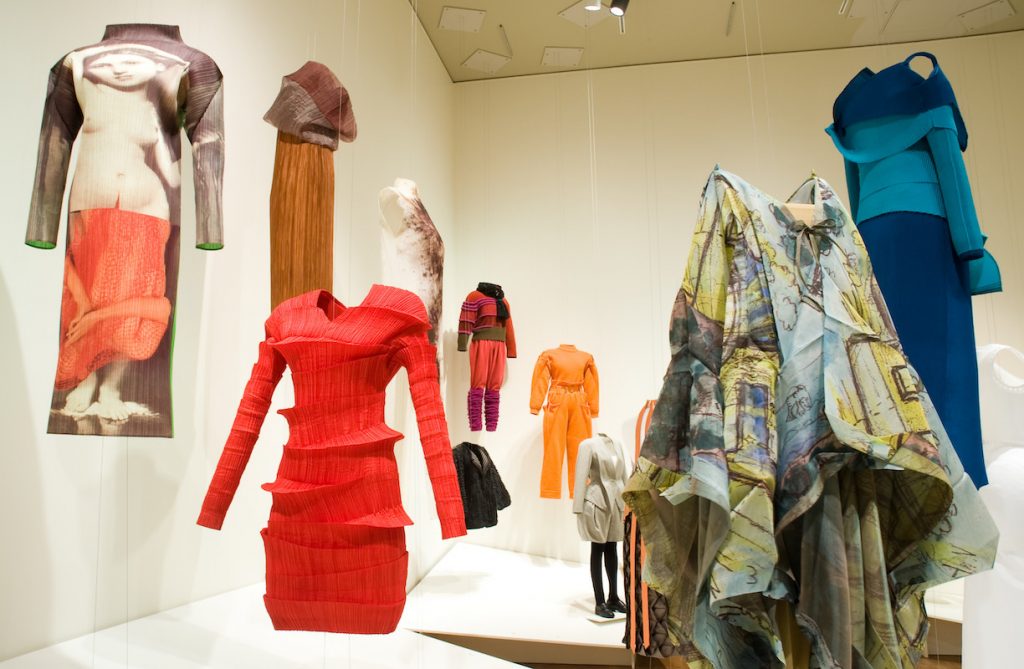 Exhibition display of dress suspended from ceiling against pale walls