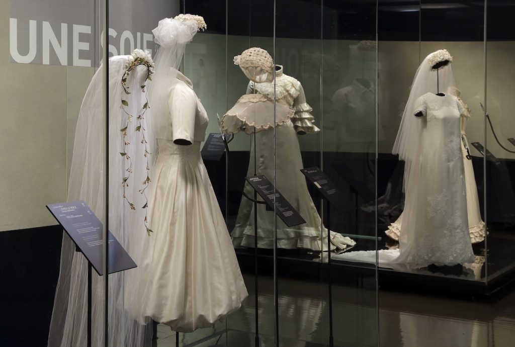 Exhibition display of dress in glass vitrine, displayed on mannequins