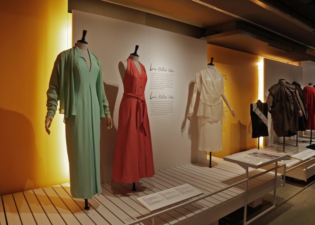 Exhibition display of 3 dress of different styles and colurs. Displayed on headless mannequins on open display