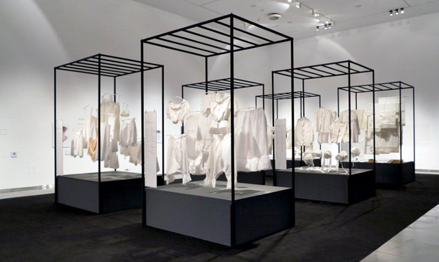 Exhibition display of white garments displayed in metal frames
