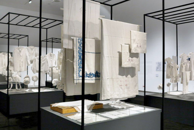 Exhibition display of white textiles displayed in metal frames