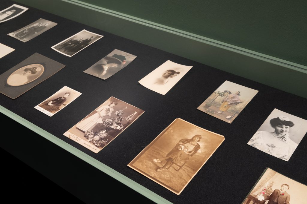 Exhibition display of 19th century looking photographs depicting wearers of roses