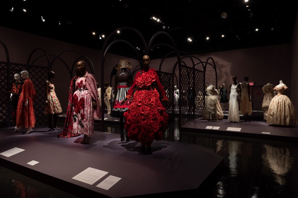 Exhibition display of dressed mannequins in rose decorated dress