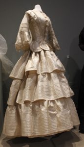 Exhibition display of dressed mannequin in long tiered gown