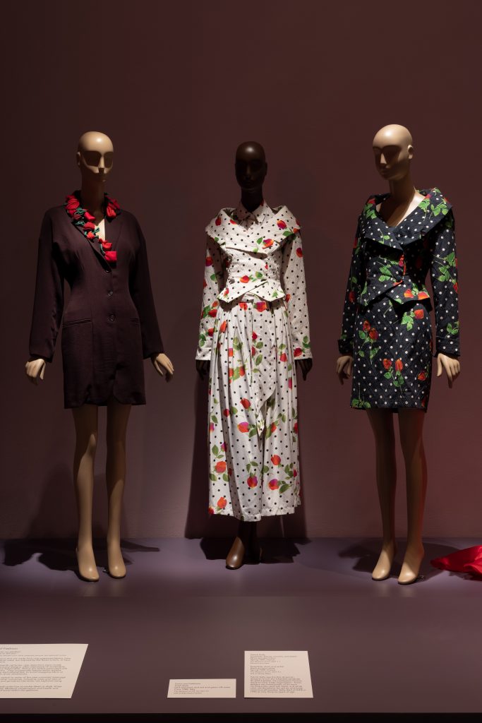 Exhibition display of dressed mannequins with rose-patterned garments