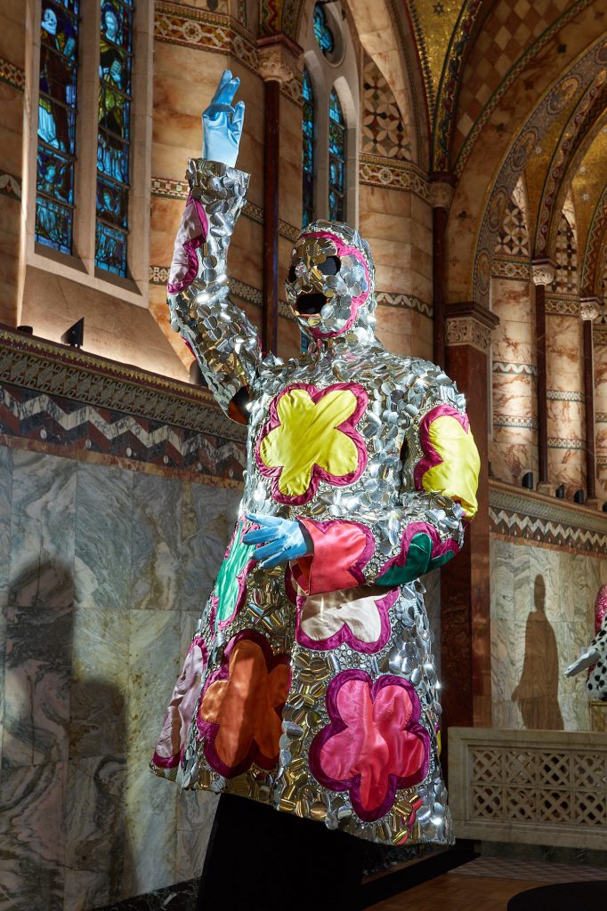 Exhibition display in church of dressed mannequin of Leigh Bowery with arm raised