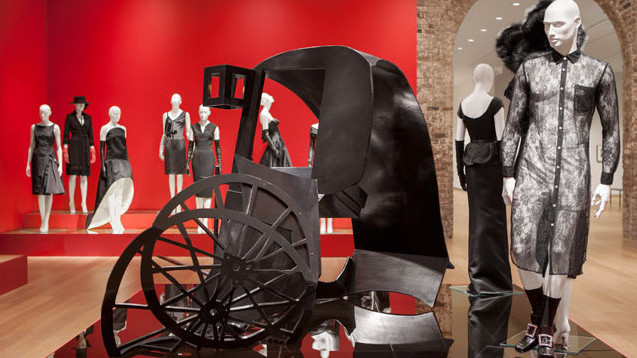 Exhibition with mannequins displaying black dresses.