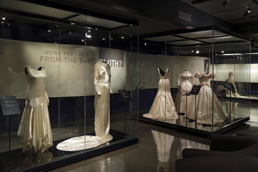 Exhibition with mannequins displayed in glass cabinets.