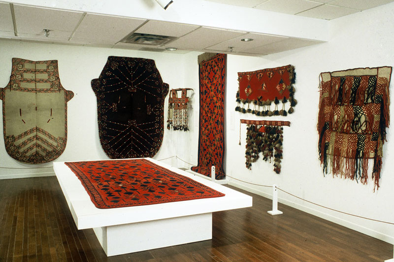 Exhibition displaying textiles on a plinth and on the two walls.