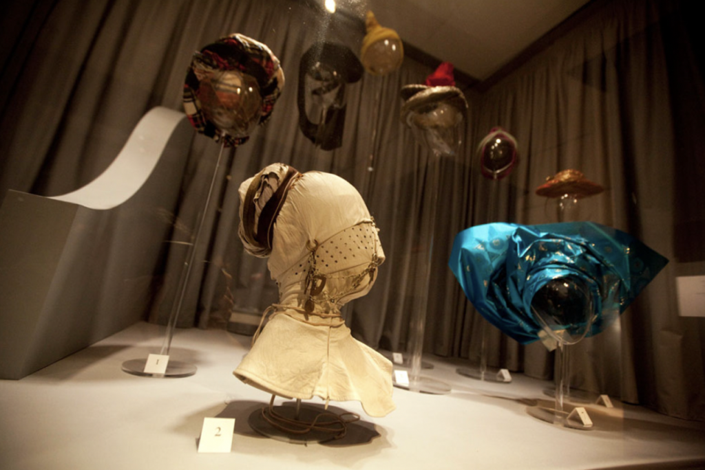 Exhibition with hats displayed in a glass cabinet.