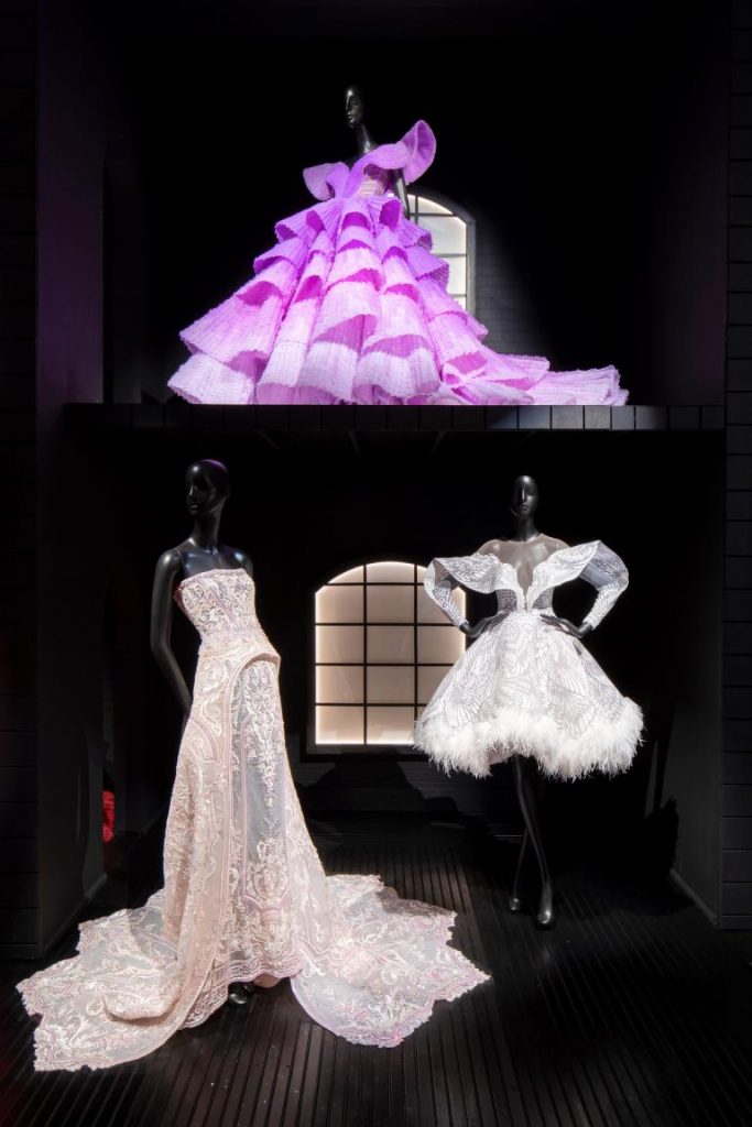 Exhibition with three mannequins displaying Michael Cinco garments.